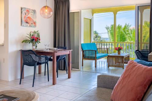 a living room with a table and chairs and a balcony at Diver's Paradise Bonaire in Kralendijk