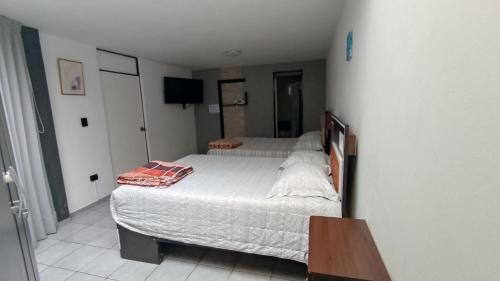 a small bedroom with two beds and a television at Departamento amplio y bonito en Arequipa 1er Piso in Arequipa
