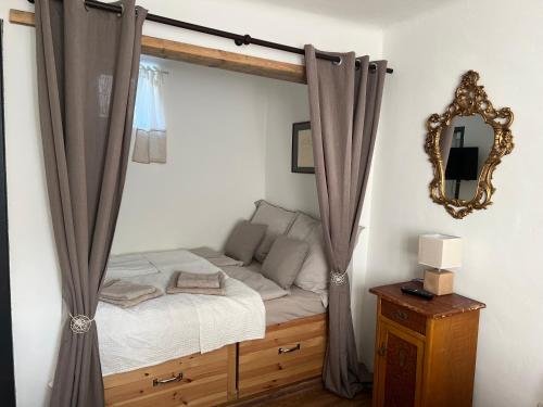 Schlafzimmer mit einem Bett mit Vorhängen und einem Spiegel in der Unterkunft Das besondere Bauernhäuschen 