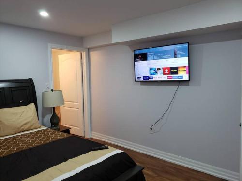 a bedroom with a bed and a flat screen tv on the wall at Luxurious 1BR - 1BA Apt Modern Bright with free parking in Brampton