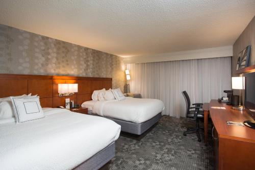 a hotel room with two beds and a desk at Courtyard by Marriott Boston Westborough in Westborough