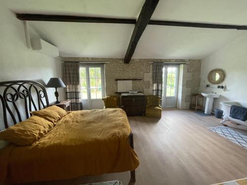 a bedroom with a bed and a desk in a room at charme de l'ancien au coeur de la vallée sud charentaise in Bardenac