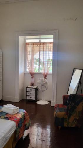 a bedroom with a window with a fan and a chair at Ventnor House Apartments in Bridgetown