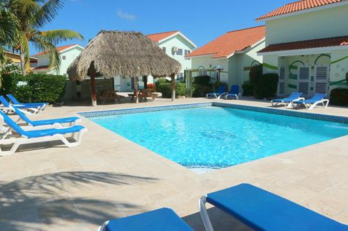 una piscina con sedie e ombrellone di paglia di Lagoon Ocean Resort 2 bdrm/2bath with beach access a Lagun