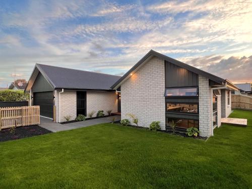 a house with a green lawn in front of it at Luxury Villa, Central, Golf and Cafés - By KOSH BNB in Hamilton
