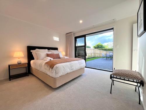 a bedroom with a bed and a large sliding glass door at Luxury Villa, Central, Golf and Cafés - By KOSH BNB in Hamilton
