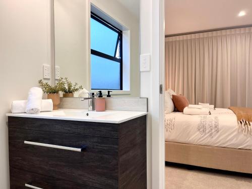 a bathroom with a sink and a bed at Luxury Villa, Central, Golf and Cafés - By KOSH BNB in Hamilton