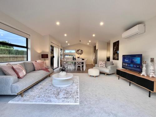 a living room with a couch and a tv at Luxury Villa, Close to Town, Walks, Golf and Cafés in Hamilton