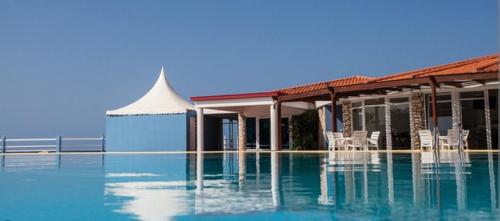 a swimming pool with chairs and a building at Vila na Mágica Baía da Murdeira in Beirona