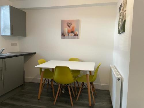a kitchen with a white table and green chairs at Amazing Studio Room 3 - Chingford/NE London in Woodford