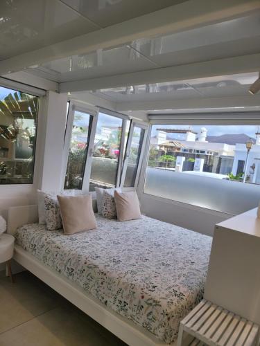 a bed in the middle of a room with windows at Un sueño in Playa Blanca