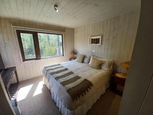 1 dormitorio con 1 cama grande en una habitación con ventana en Casa Pucon sector Laguna ancapulli en Pucón