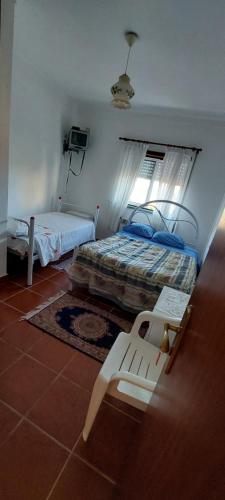 a bedroom with two beds and a bench in it at Alojamento da Avó Maria in Pombal