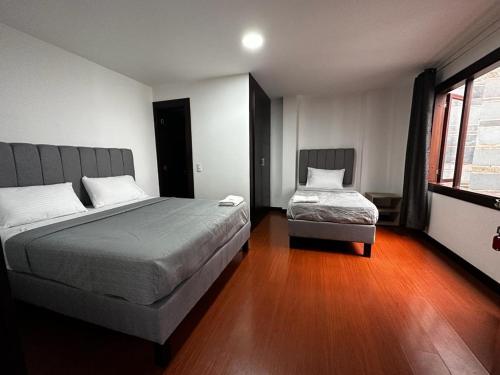 1 dormitorio con 2 camas y ventana en Hotel The MIRROR, en Bogotá