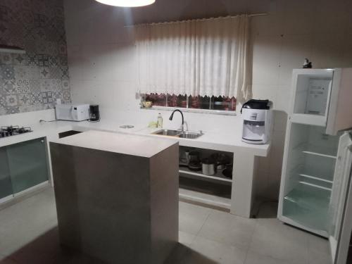 La cuisine blanche est équipée d'un évier et d'un réfrigérateur. dans l'établissement Recanto das pedras, à São Thomé das Letras