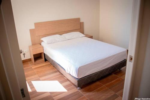 a small bedroom with a bed and a wooden floor at Vive Piura a tu manera in Piura