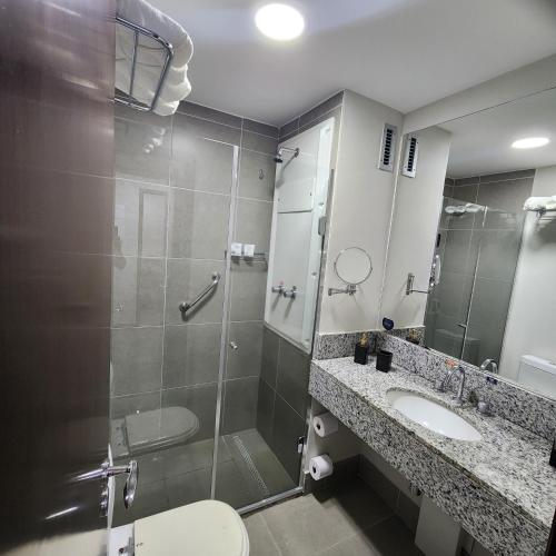 uma casa de banho com um chuveiro, um WC e um lavatório. em Suíte Premiere no Rio de Janeiro