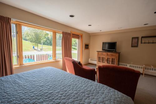 a bedroom with a bed and chairs and a television at Sugarloaf Inn in Carrabassett