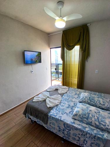 a bedroom with a bed with a ceiling fan and a window at Flat 02 com Varanda - Avenida Hospedagem in São Thomé das Letras