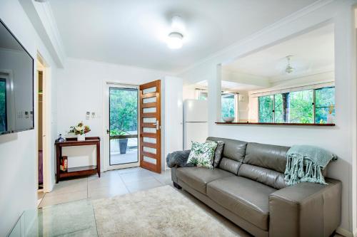 a living room with a couch and a fireplace at Airlie Beach Eco Cabins - Adults Only in Airlie Beach