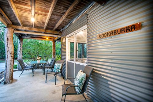a covered patio with a table and chairs on it at Airlie Beach Eco Cabins - Adults Only in Airlie Beach