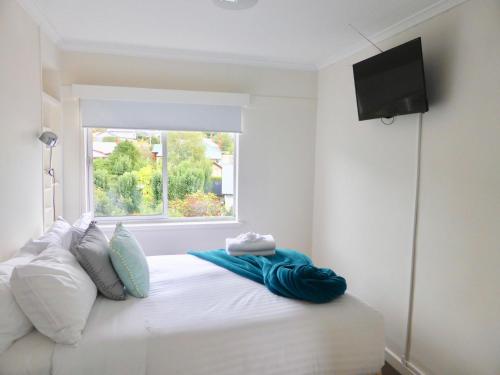 a bedroom with a white bed with a window at View Street Vista location parking and views in Sandy Bay