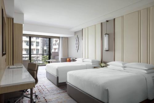 上海市にある上海 マリオット ホテル ホンチャオのベッド3台とデスクが備わるホテルルームです。