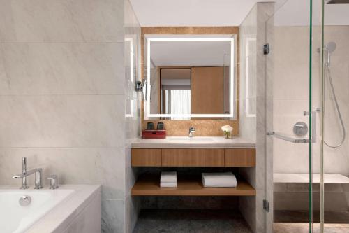 a bathroom with a tub and a sink and a mirror at Shanghai Marriott Hotel Hongqiao in Shanghai