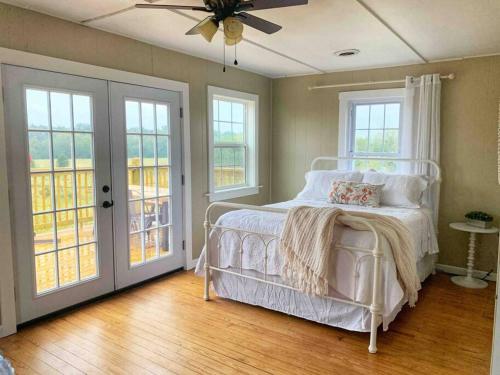 1 dormitorio con cama, ventanas y ventilador de techo en Green Acres Farmhouse Fugitive Beach/Military/MS&T, en Rolla