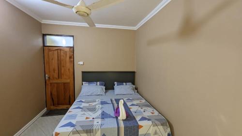 1 dormitorio con 1 cama con ventilador de techo y puerta en BabaJay Family Home, en Dar es Salaam