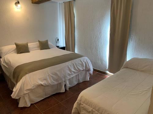 ビージャ・ラ・アンゴストゥーラにあるDel Caballero Hotelのベッド2台と窓が備わるホテルルームです。