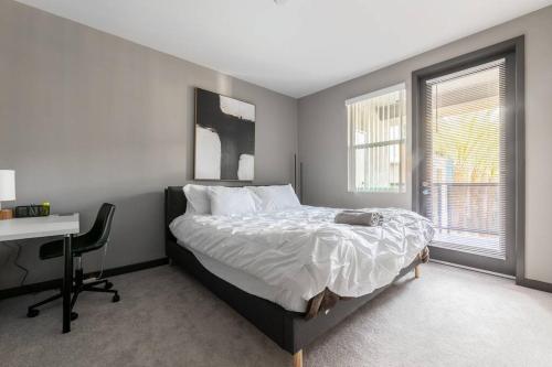 a bedroom with a bed and a desk and two windows at Private, Modern Luxury 2 Bd/ 2 Ba in Santa Ana