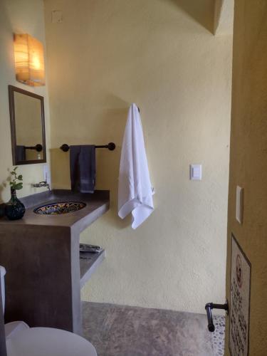 Baño con una toalla blanca colgada en la pared en ORidleys Hostel16, en Barra de Potosí