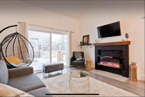 a living room with a fireplace and a tv at Cap Magog! Près du lac Memphrémagog et Mont Orford in Magog-Orford