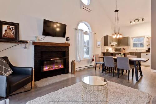a living room with a fireplace and a dining room at Cap Magog! Près du lac Memphrémagog et Mont Orford in Magog-Orford