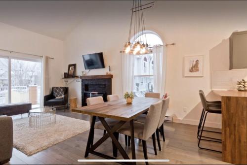 a dining room and living room with a table and chairs at Cap Magog! Près du lac Memphrémagog et Mont Orford in Magog-Orford