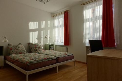 a bedroom with a bed and two windows with red curtains at Omas Linde in Brandenburg an der Havel