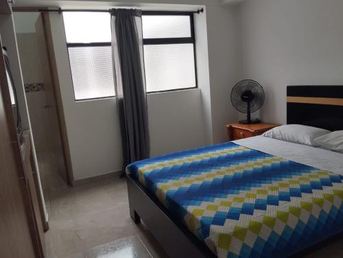 a bedroom with a bed and two windows and a door at Habitación doble con baño privado in Sabaneta