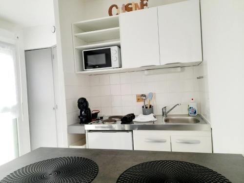 une petite cuisine avec des armoires blanches et un évier dans l'établissement Studio cosy gare Perpignan, à Perpignan