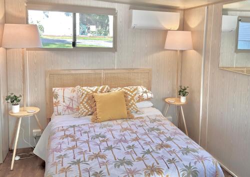 a bedroom with a bed and two tables with lamps at Mornington Peninsula Retro Caravans in Rye