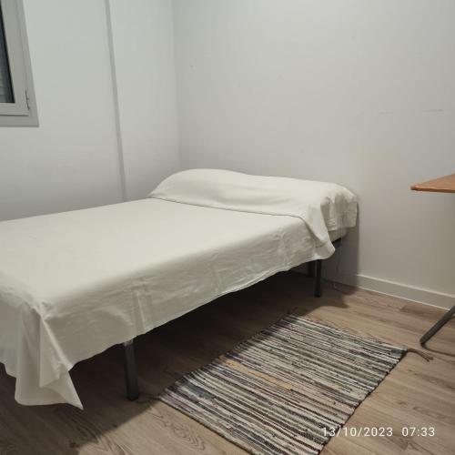 Una cama con una sábana blanca en la parte superior de una habitación en Casa particular Tatiana en Badalona