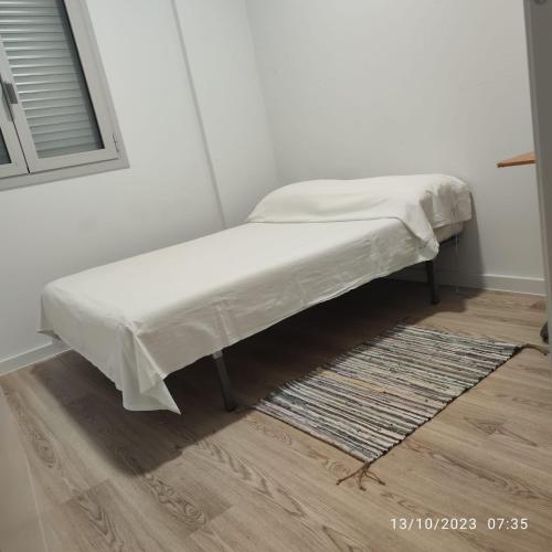 a bed with a white sheet on top of a room at Casa particular Tatiana in Badalona