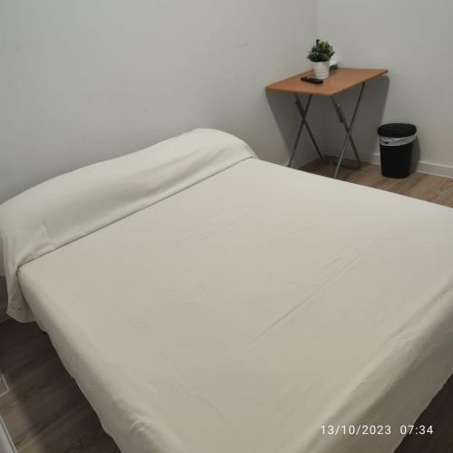a white bed with a table in a room at Casa particular Tatiana in Badalona