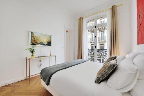 a white bedroom with a bed and a window at Eiffel Tower 5 bedrooms 10 guests with 2 Carpark in Paris