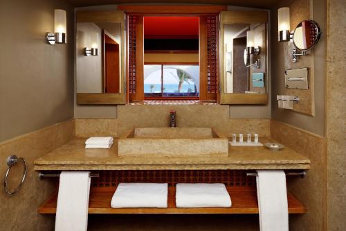Retac Qunay Dahab Resort & SPA في دهب: حمام مع حوض ومرآة كبيرة