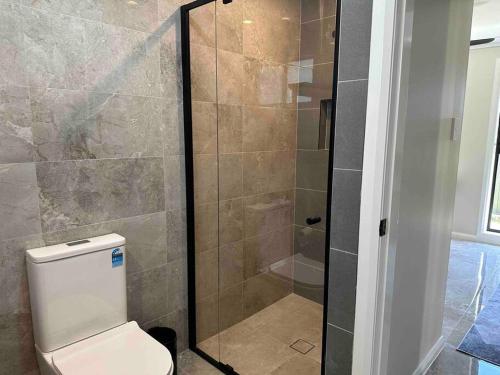 a bathroom with a toilet and a glass shower at Granny Guest house Sydney Blue Mount in Kingswood