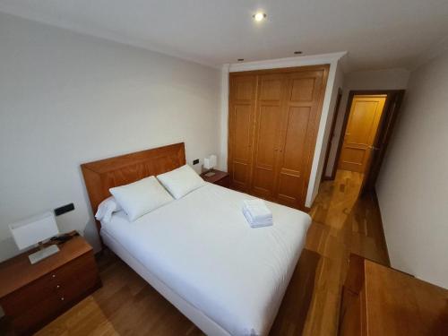 um quarto com uma cama branca e uma porta de madeira em Calle Areal muy céntrico em Vigo