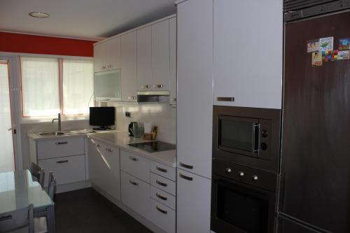 una cocina con armarios blancos y un aparato negro en Calle Areal muy céntrico en Vigo