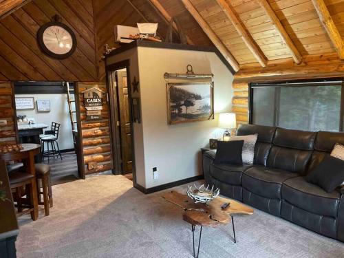 a living room with a leather couch and a table at Little Cabin in the Woods. in Post Falls