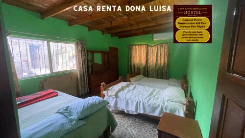 Habitación verde con 2 camas y un cartel en la pared en Casa Renta Dona Luisa Hostel, en Mulegé